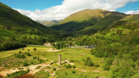 aerial flyover of the glenfinnan monument towards glenfinnan viaduct in scottish highlands, scotland, united kingdom