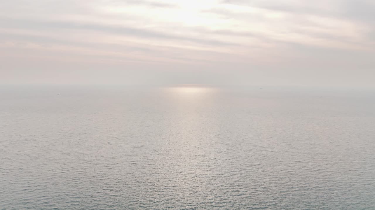 Calm sea surface stretches endlessly under pastel morning light near Kaoh Rong Sanloem, Cambodia, with gentle sunlight reflecting softly on the water in a peaceful aerial view