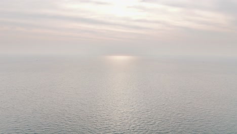 calm sea surface stretches endlessly under pastel morning light near kaoh rong sanloem, cambodia, with gentle sunlight reflecting softly on the water in a peaceful aerial view