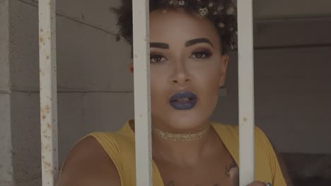latin woman, with tattoos, reaching out a hand from behind bars in search of help. zoom out
