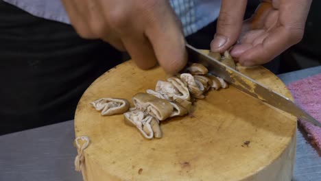 cortar órganos de cerdo intestino con un cuchillo en el mercado nocturno de tailandia puesto de comida