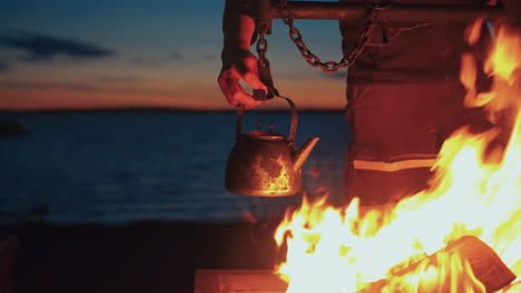 hombre colgando tetera sobre la chimenea junto al mar