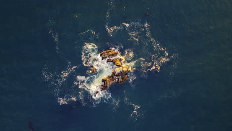 Hermosa-Vista-De-Pájaro-De-Arriba-Hacia-Abajo-Del-Agua-Que-Se-Lava-Sobre-Las-Rocas-En-El-Océano