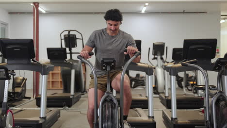 man stretching while using assault bike. - static shot