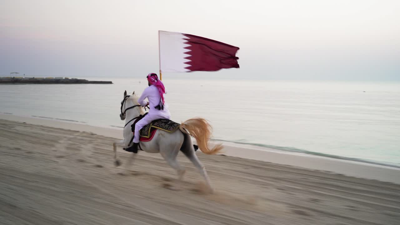 un caballero montando un caballo corriendo y sosteniendo la bandera de qatar cerca del mar-4