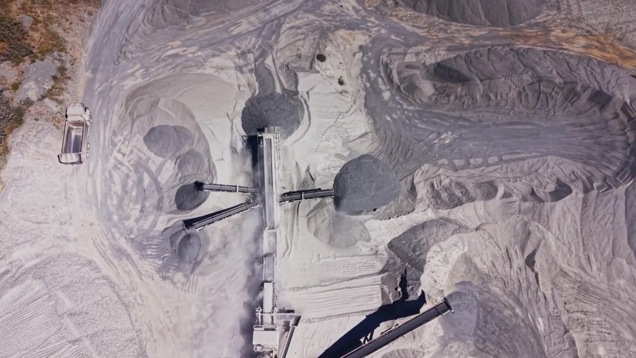 Dusty landscape of a large mining site shows machinery and piles