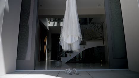 a wedding dress and her shoes hanging at the entrance to a luxurious house, the wedding is being prepared