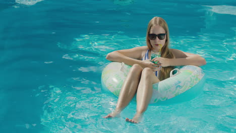 a teenage girl floats in an inflatable circle on the surface of the pool