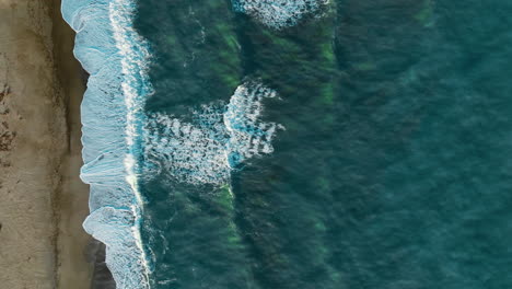 long ocean waves crash repeatedly on the sandy coast of the continent, overhead