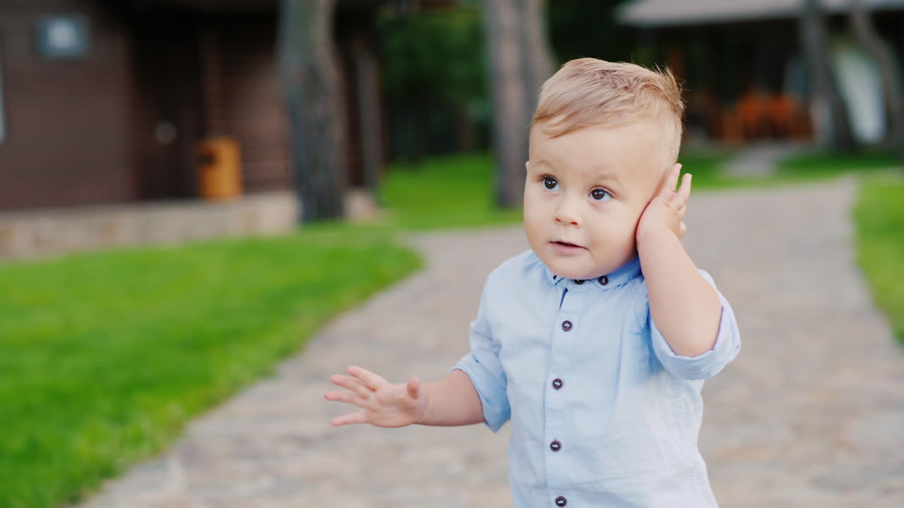 Un bambino simpatico gioca con le chiavi della macchina, parla come al telefono come un piccolo uomo d'affari 4K