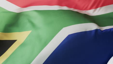 white rugby ball rolling over waving flag of south africa with copy space, in slow motion