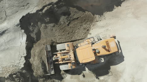 Top-Down-View-of-Front-Loader-Scooping-Sand-from-Pile-during-Daytime