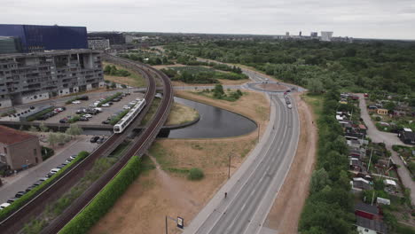 An-urban-area-where-the-metro-runs-above-ground,-offering-a-captivating-view-of-the-bustling-traffic-on-the-roads,-a-roundabout,-and-the-backdrop-of-nature-in-the-distance