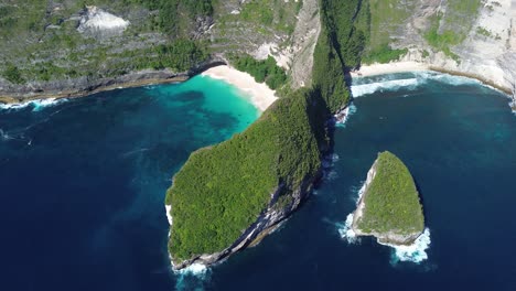 drone footage capturing a wide aerial orbit of kelingking beach in bali, indonesia, highlighting the turquoise waters, dramatic cliffs, and the surrounding landscape