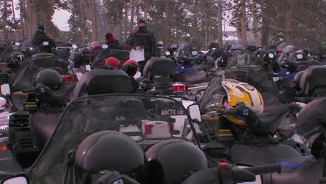 many snowmobiles are lined up in a snowmobile parking lot