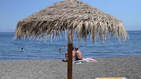 a single straw beach umbrella on a black sand beach