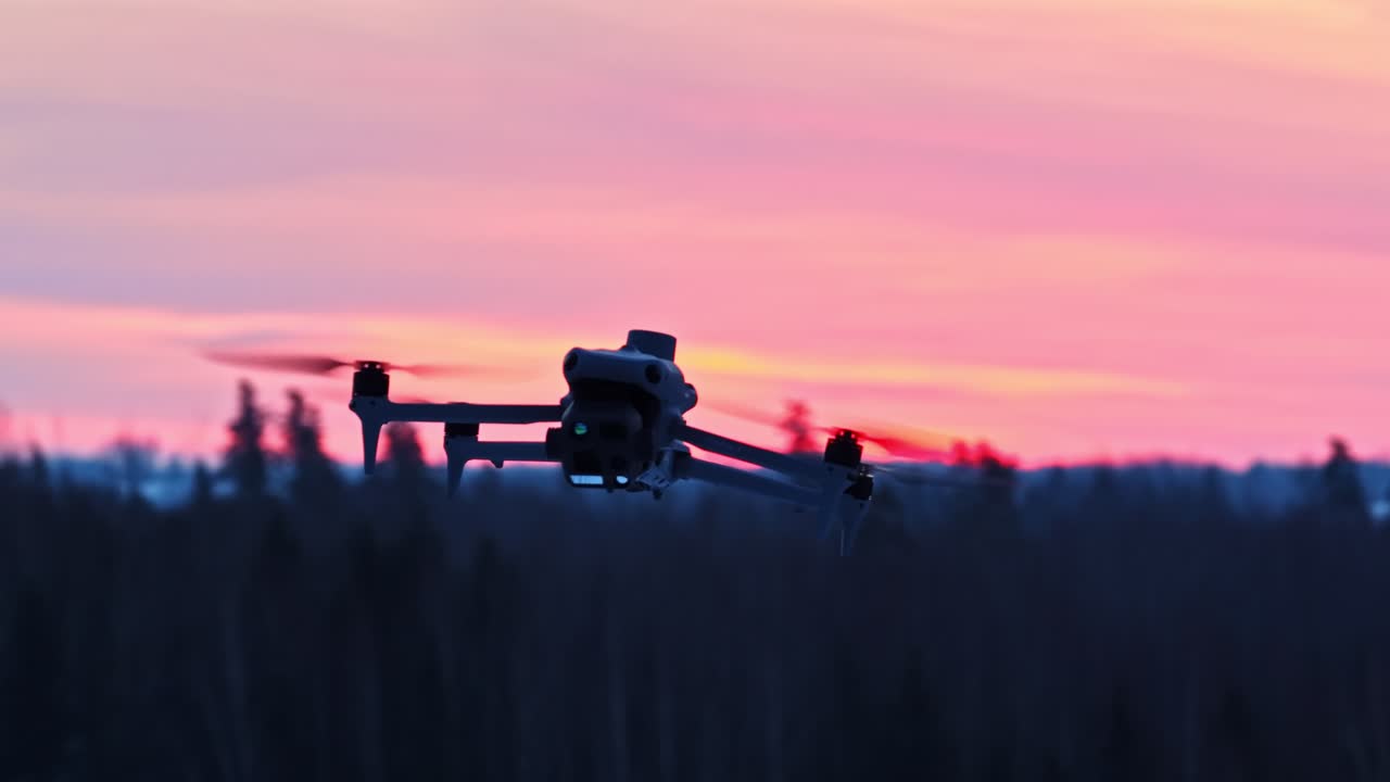 En moderne drone flyver lavt med en lyserød solnedgang i baggrunden. Nærbillede