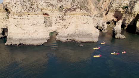 aerial shot flying over people kayaking on the coast of lagos in portugal