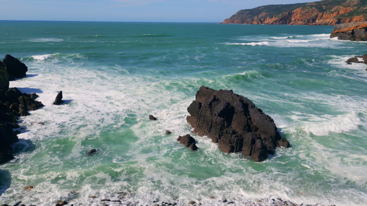 las olas espumosas del dron rodando en la costa pedregosa en cámara lenta. la costa lavada por el mar