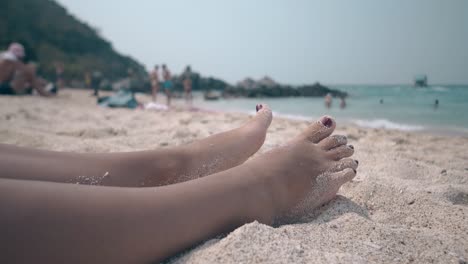 woman with red pedicure sunbathes and sleeps on sand beach