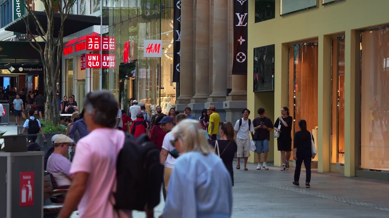 Shoppers shopping at bustling Queen street mall, an outdoor pedestrian shopping precinct, a vibrant urban street scene of downtown Brisbane city on the weekend, slow motion shot.