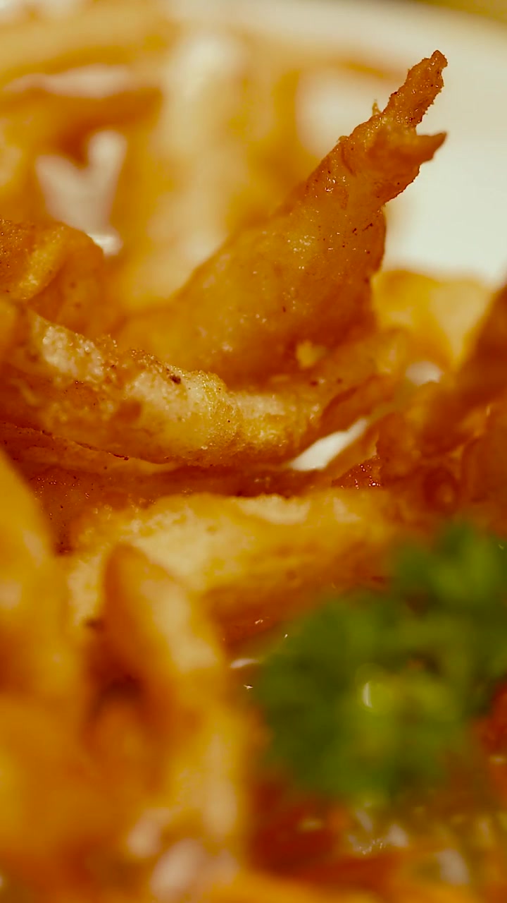 Primo piano estremo di snack fritti dorati, caratterizzati da una consistenza croccante e un'illuminazione calda.