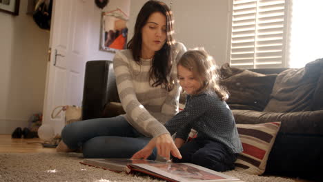 mother and daughter at home looking through photo album