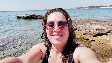 happy woman vlogging her sunny beach day at vouliagmeni