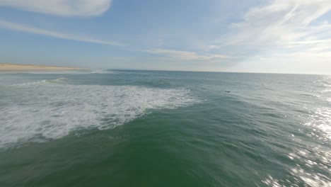 Drone-flying-around-isolated-surfer-on-surfboard-waiting-for-waves,-Soustons-in-Landes-department,-France