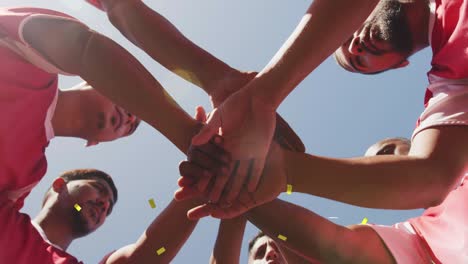 animation of confetti falling over male football team stacking hands on pitch