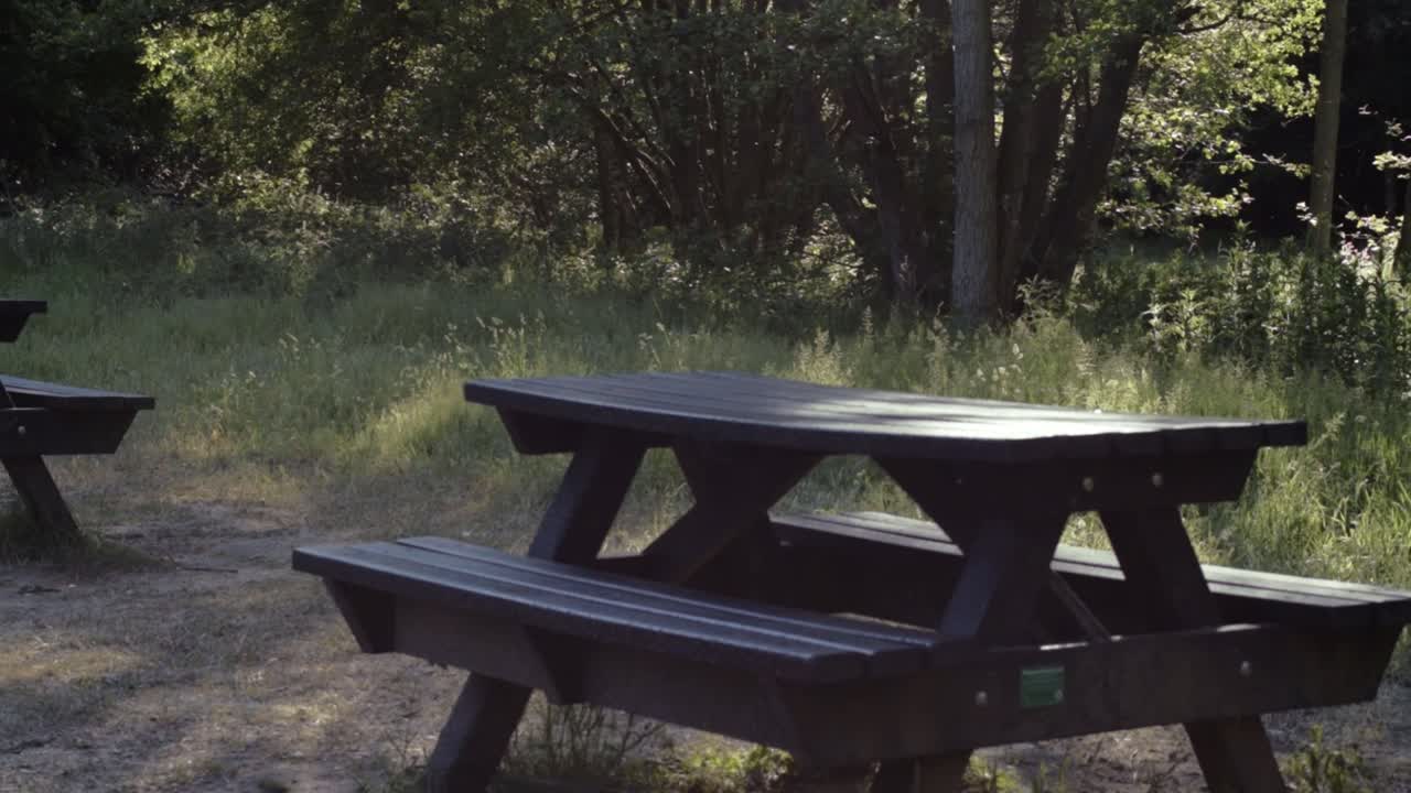 Empty wooden picnic tables in park land medium panning shot