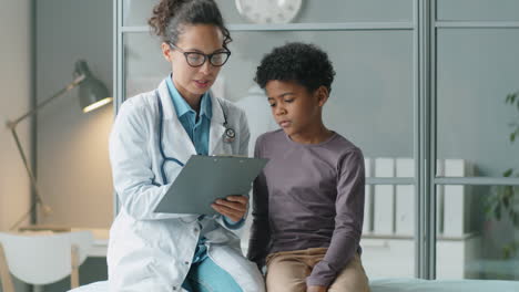 african american kid talking with female doctor on consultation in clinic