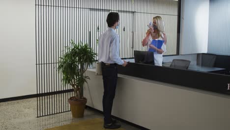 mujer de negocios caucásica con máscara facial comprobando la temperatura de sus compañeros de trabajo