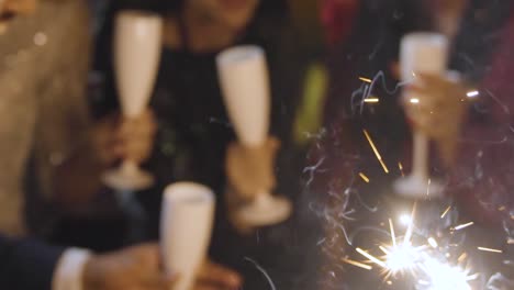 close up of friends celebrating new years eve with champagne sparklers