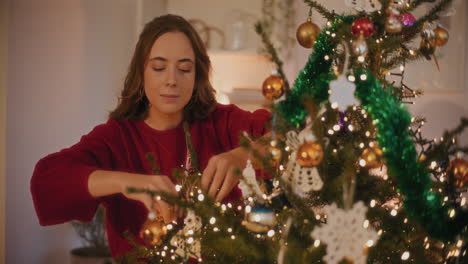 Mujer-Atando-Adornos-Navideños-En-El-árbol