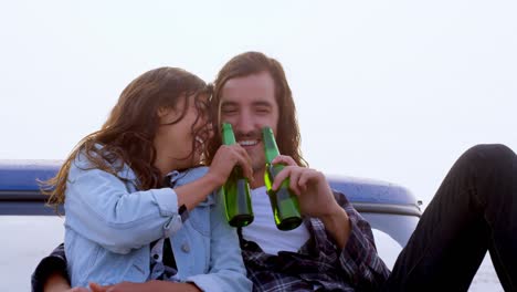 Couple-having-beer-while-sitting-on-car-bonnet-4k