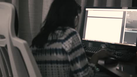 una mujer está trabajando en una computadora y escribiendo en un teclado - trabajo desde casa