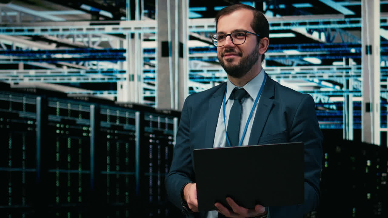 IT-professionel smiler og arbejder på bærbar computer i datacenter