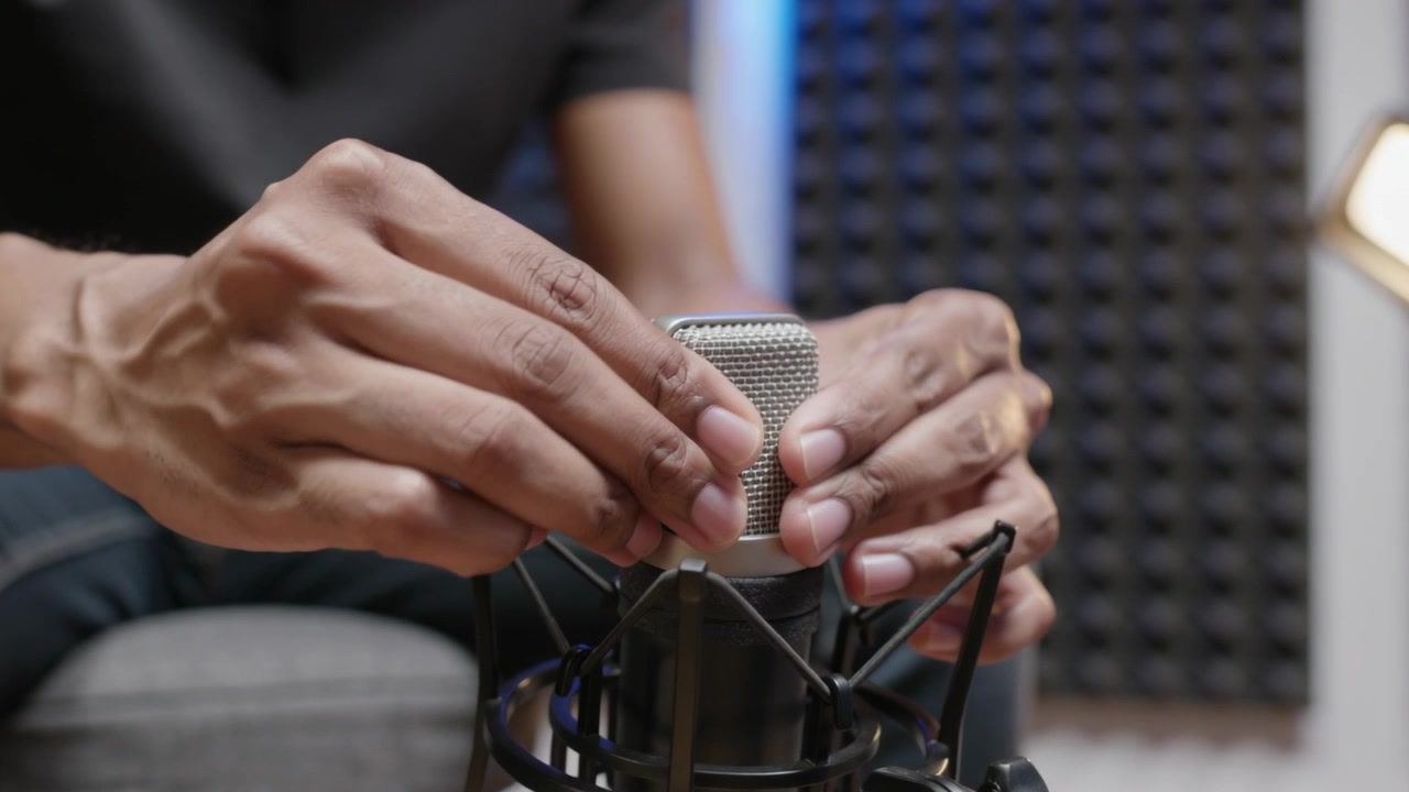 Lowering tech hands positioning mic capsule into shock mount in studio preparing to record
