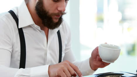 un hombre de negocios casual usando una máquina de escribir y bebiendo café.