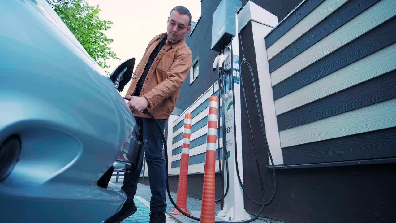 Processo di rifornimento di un'auto elettrica. Inquadratura sotto lo sportello in cui si ricarica l'auto elettrica ecologica. Lo sportello di ricarica dell'auto elettrica si apre automaticamente. Una mano maschile inserisce un'auto erettile