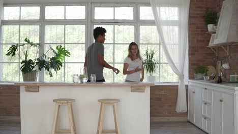 morning at home happy young couple dancing listening to music in the kitchen wearing pajamas. multi ethnic couple in love