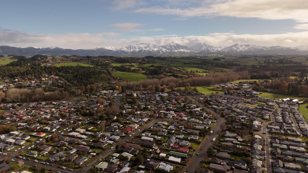 A stable 4K 60fps aerial shot of Geraldine town in the Canterbury region of New Zealand's South Island. The majestic, snow-covered Southern Alps provide a stunning background