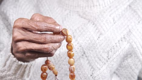 elderly hands holding rosary beads