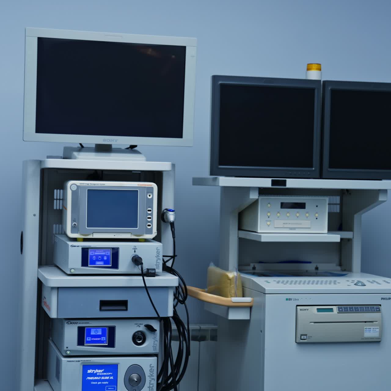 Advanced equipment with screens and monitors necessary for modern surgeries. White wall of surgery room at backdrop