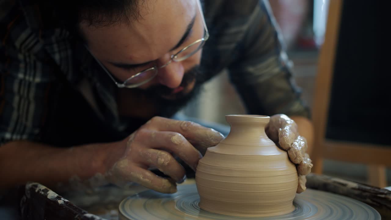 Close-up of skillful potter decorating ceramic bowl on throwing wheel working alone