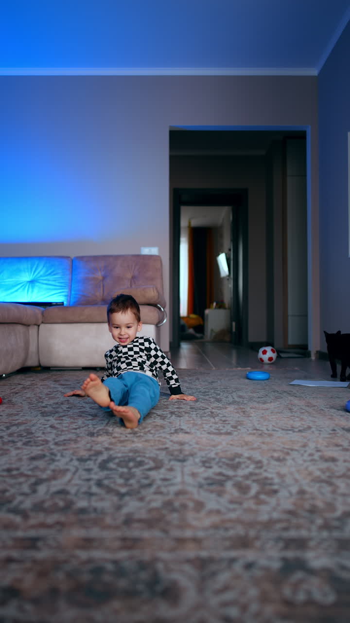 Smiling Caucasian baby boy lies on the floor at home playing with his toys. Joyful game for a toddler with pyramid rings. Vertical video.
