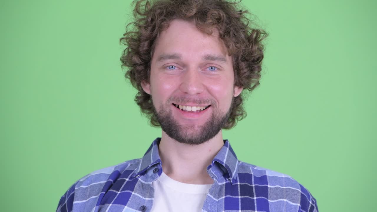 Young handsome bearded hipster man with curly hair