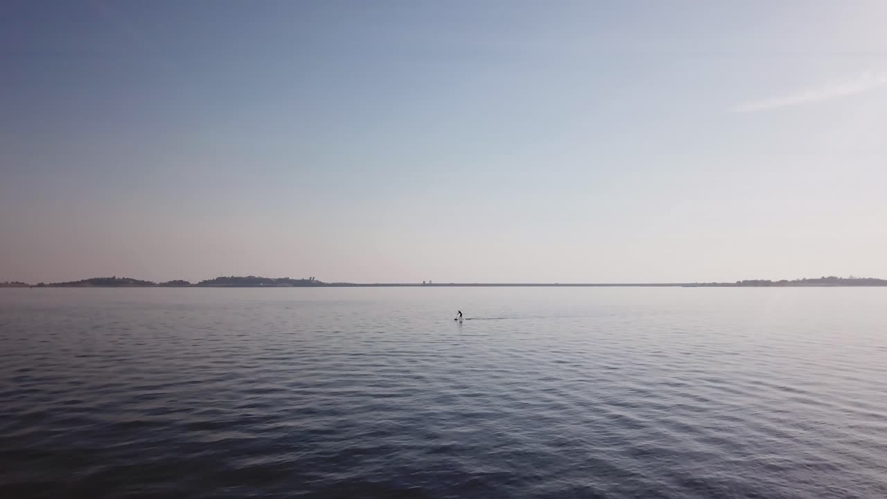 평온 한 호수 에서 스탠드업 패들보드 를 타고 있는 사람