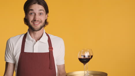 caucasian waiter in front of camera on yellow background.